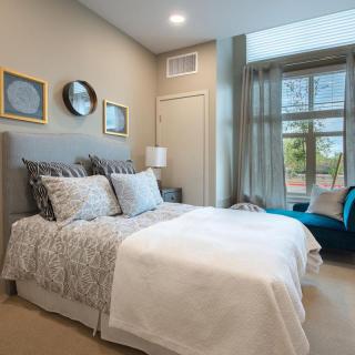 A cozy and well-decorated bedroom featuring a comfortable bed, elegant decor, and a large window providing natural light.