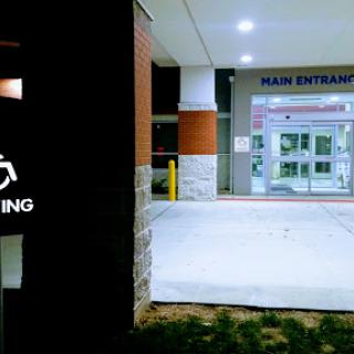 Main entrance with accessible parking sign at night.