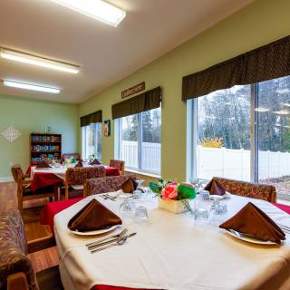 A cozy dining room with elegantly set tables and large windows offering a view outside.
