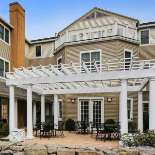 A residential building with a charming patio featuring a pergola and outdoor seating.