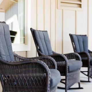 A row of comfortable wicker rocking chairs arranged neatly on a porch.