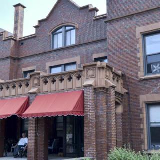 A historic brick building featuring a balcony with red awnings.