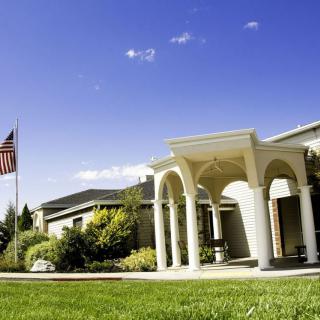 A building with columns and a flagpole in a landscaped setting under a clear blue sky.