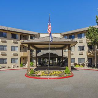 The entrance of a hotel building with an American flag and well-maintained landscaping.