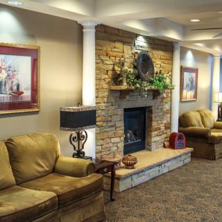 A cozy living room featuring a stone fireplace, comfortable couches, and decorative art pieces.