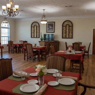 A formal dining area with neatly arranged tables and chairs, featuring elegant decor and well-set tableware.
