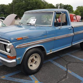 A classic blue Ford pickup truck from the 1970s, showcased at a car event.