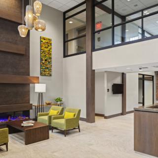 A modern lobby with stylish furnishings, featuring a seating area and a decorative fireplace.