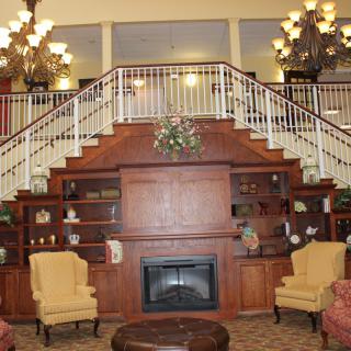 Cozy lobby with a central fireplace and grand staircase.