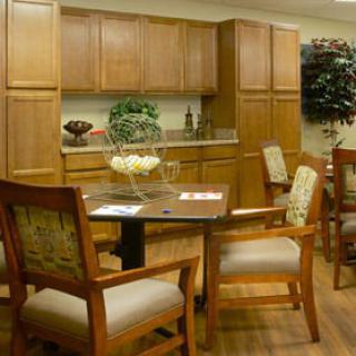 A cozy kitchen area with wooden cabinets, a dining table, and upholstered chairs.