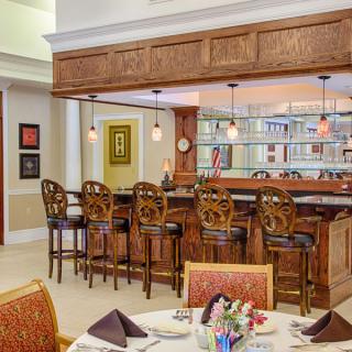 A cozy restaurant interior featuring a wooden bar with high chairs and a dining table set elegantly in the foreground.