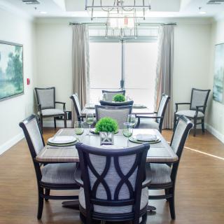 A well-decorated dining room with stylish chairs and a central table, featuring elegant light fixtures and artwork on the walls.