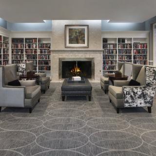 A cozy library space with a fireplace, surrounded by bookshelves and comfortable seating.