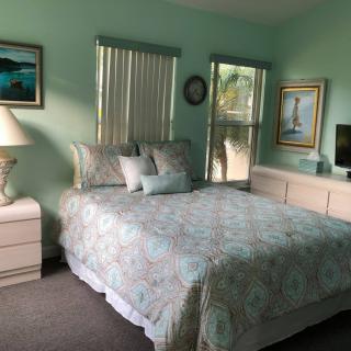 A cozy bedroom with a neatly made bed, paintings on the walls, and soft lighting.
