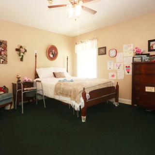 A cozy bedroom with a neatly made bed, a dresser, and various wall decorations.