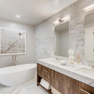 A modern bathroom featuring a freestanding bathtub, spacious double sink vanity with mirrors, and elegant marble accents.