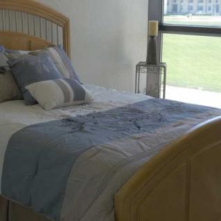 A cozy bedroom with a neatly made bed and large window allowing natural light.