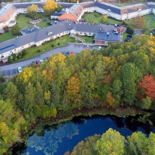 An aerial view of buildings surrounded by colorful autumn trees and a small lake.