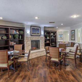A cozy living room with a fireplace, seating area, and bookshelves on a wooden floor.