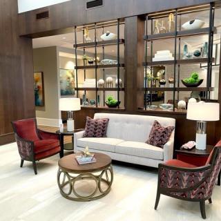 A modern lobby featuring stylish seating with a sofa and armchairs, accented by decorative shelves and elegant lighting.