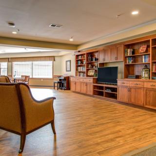 A spacious and cozy living room with wooden floors, built-in bookshelves, and a large television.
