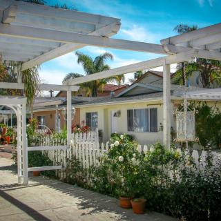 A charming residential area with houses, a white picket fence, and vibrant gardens.