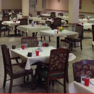 An empty dining area with tables and chairs set up for a meal.