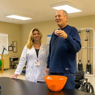 A healthcare professional assists a patient in a rehabilitation setting.
