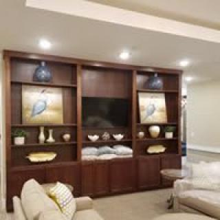 A modern living room with an entertainment center, featuring shelves with decorative items and cozy seating.
