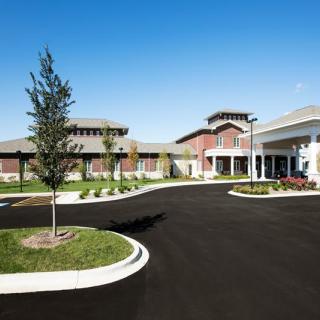 A modern building with a landscaped entrance and spacious parking lot.