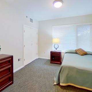 A minimalist bedroom with a bed, nightstand, and dresser.
