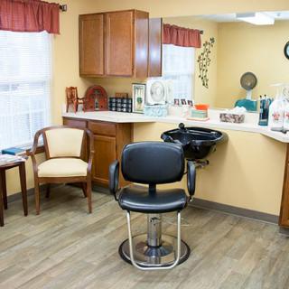 A cozy hair salon with a barber chair, sink, and waiting area.