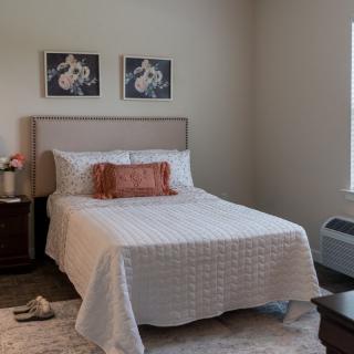 A modern and minimalist bedroom with a neatly made bed and simple decor.