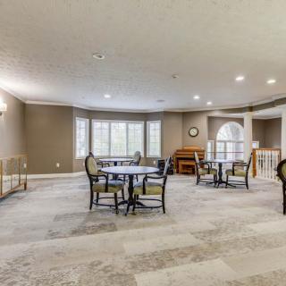 A spacious and well-lit dining area with several tables and chairs, featuring large windows and a neutral color palette.