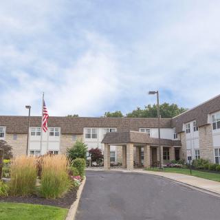 The exterior of a two-story building with an entrance, surrounded by landscaping and a flag.