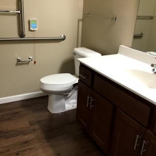 A clean and accessible bathroom featuring a toilet, sink, and grab bars.