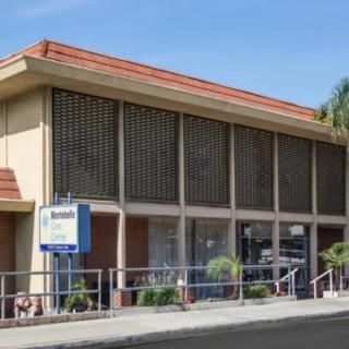 Street view of a motel building with large windows and a sign.