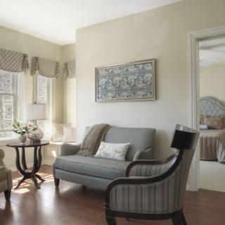 A cozy living room with a sofa, armchairs, and a coffee table, featuring soft lighting and elegant decor.