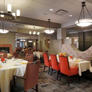 A well-lit restaurant dining area featuring neatly arranged tables and chairs with elegant decor.