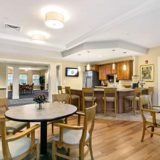 A cozy dining area with a kitchen setup, featuring wooden flooring and comfortable seating.