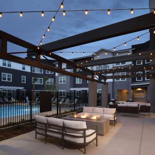 Modern outdoor patio with comfortable seating and string lights by a pool.