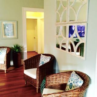 A cozy living room with wicker chairs, mirror decor, and hardwood floors.