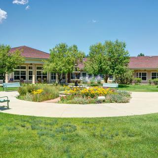 A landscaped garden with a pathway, benches, and a building in the background.