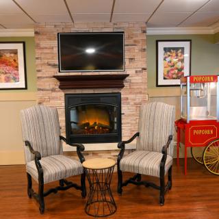 A cozy living room interior featuring a fireplace, two striped chairs, and a popcorn machine.