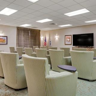 A modern meeting room with comfortable chairs arranged in front of a large television.