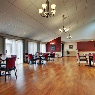 A spacious dining room with wooden floors, elegant lighting, and dining furniture.