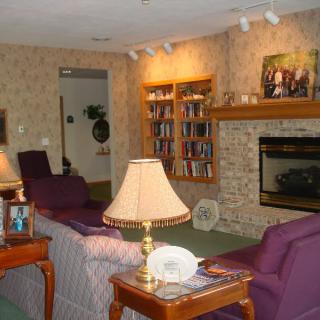 A cozy living room with a fireplace, bookshelf, and comfortable seating.