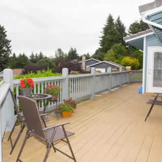 A spacious outdoor deck with chairs and plants, surrounded by trees.