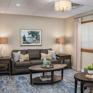 A cozy living room with neutral tones, featuring a sofa, coffee table, and lamps.