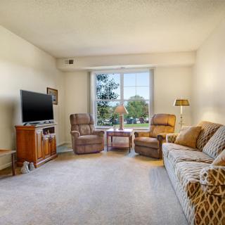 A cozy living room featuring a comfortable sofa, relaxing chairs, and ample natural light from the window.